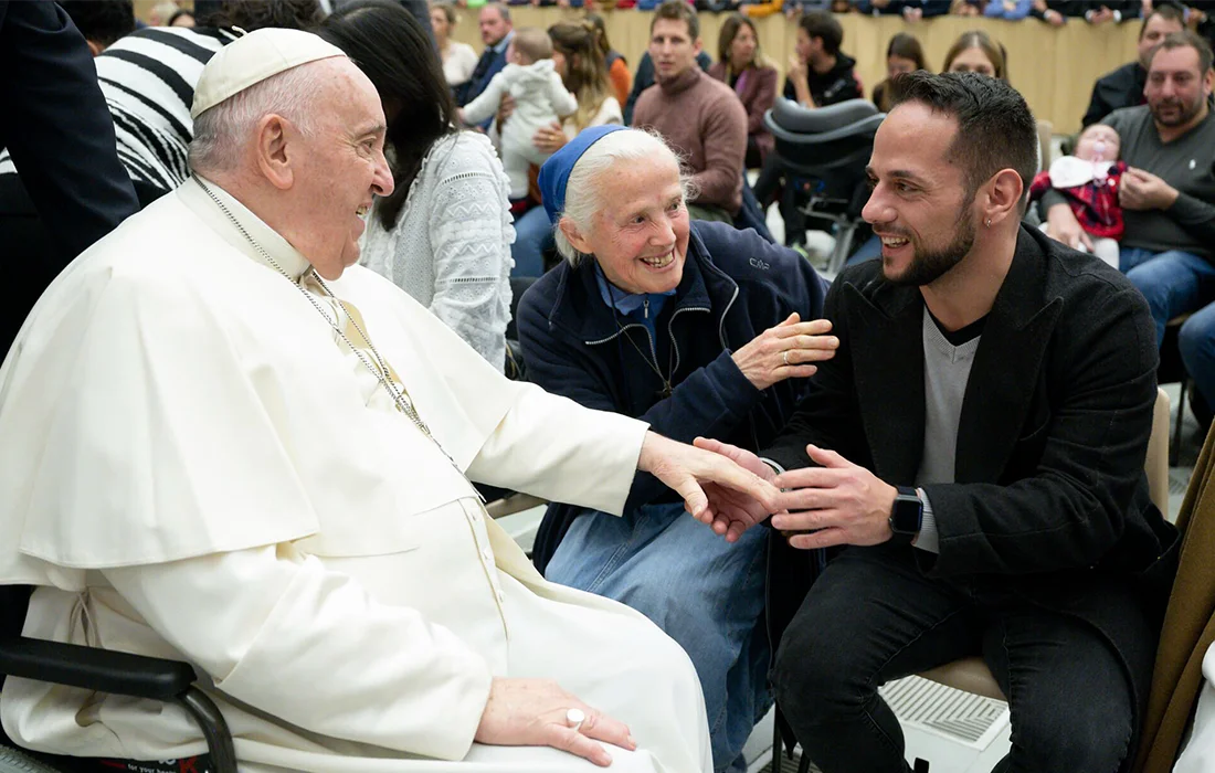 Le pape François salue Tiziano et une femme plus âgée dans l'assistance.