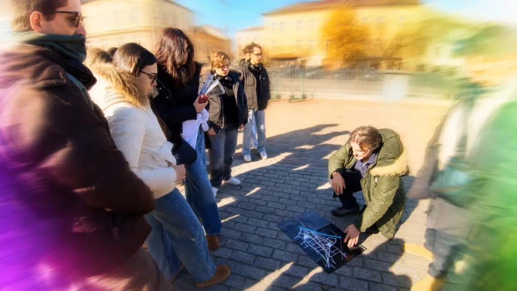 Marco Reglia zeigt jungen Menschen eine Karte und vermittelt queere Geschichte bei einem Stadtrundgang
