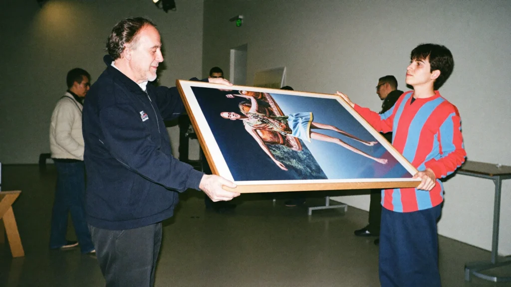 Zwei männliche Partner mit Altersunterschied installieren gemeinsam ein Bild in einem Wiener Ausstellungsraum.