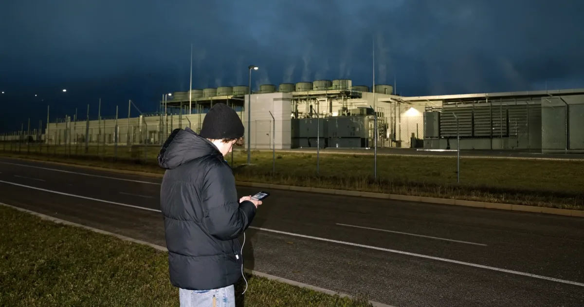 Ein Smartphone liegt neben Kabeln und Kühlsystemen einer technischen Serveranlage.