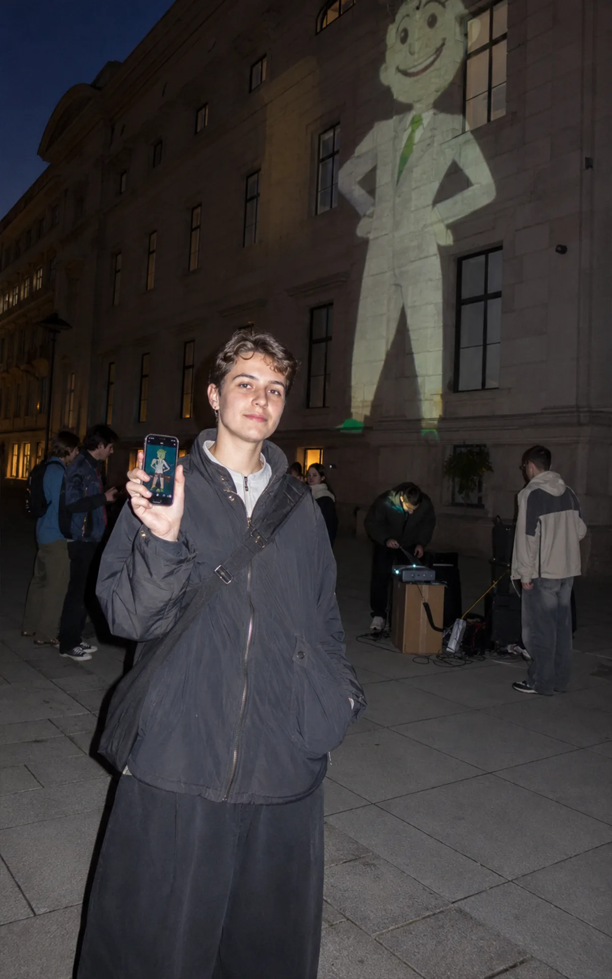Eine junge Person fotografiert in Wien eine absurde PR-Installation vor einem institutionellen Gebäude.