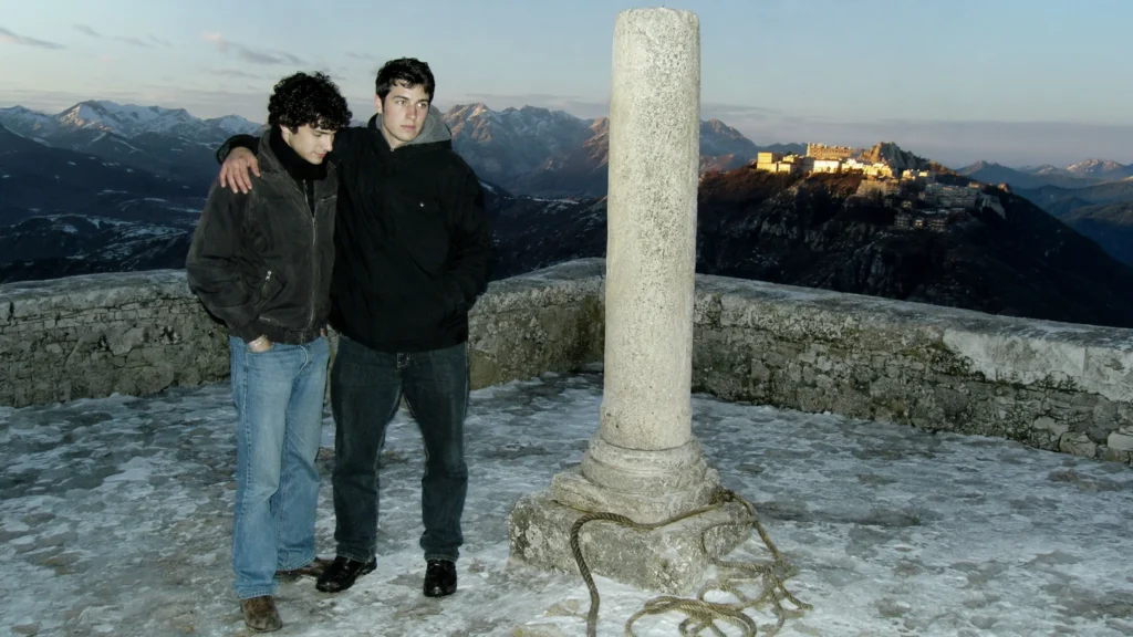 Zwei junge Männer stehen frei neben einer gelösten Fessel vor dem Heiligtum von Montevergine.