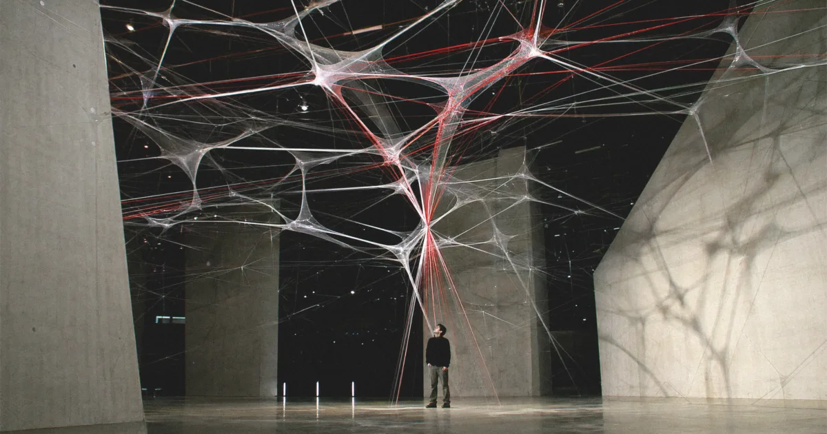 Eine Person steht in einer Wiener Installation, während ein heller Alarmweg die Energie eines großen Netzwerks auf sich konzentriert.