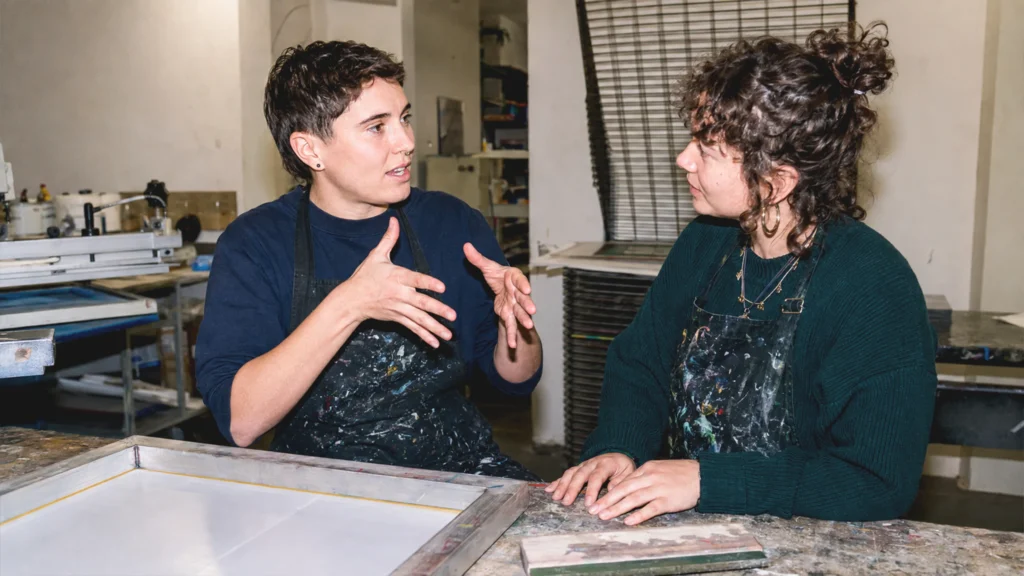 Eine gehörlose Person führt in einem Wiener Siebdruckatelier ein Gespräch in Österreichischer Gebärdensprache.