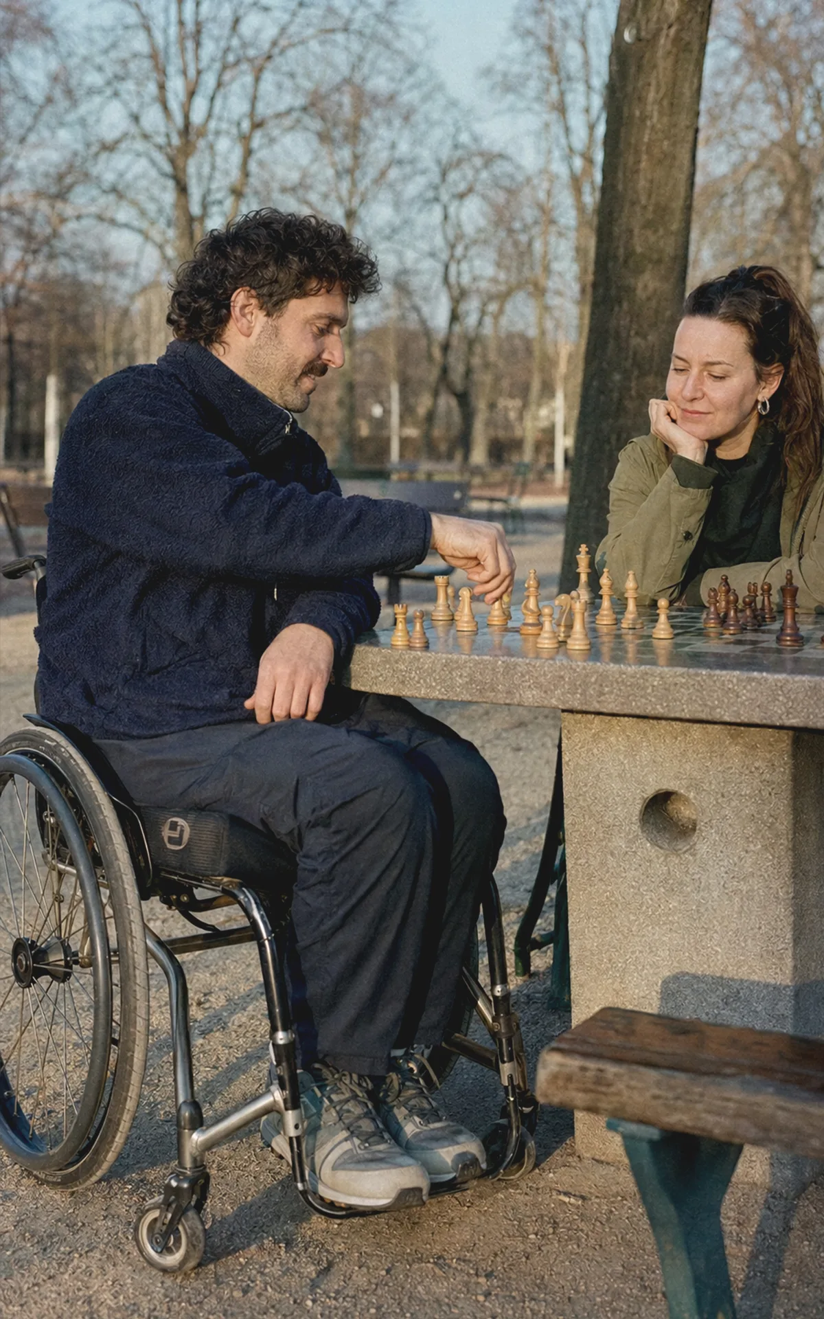 Ein Rollstuhlnutzer spielt im Wiener Augarten Schach mit einer vertrauten Person.