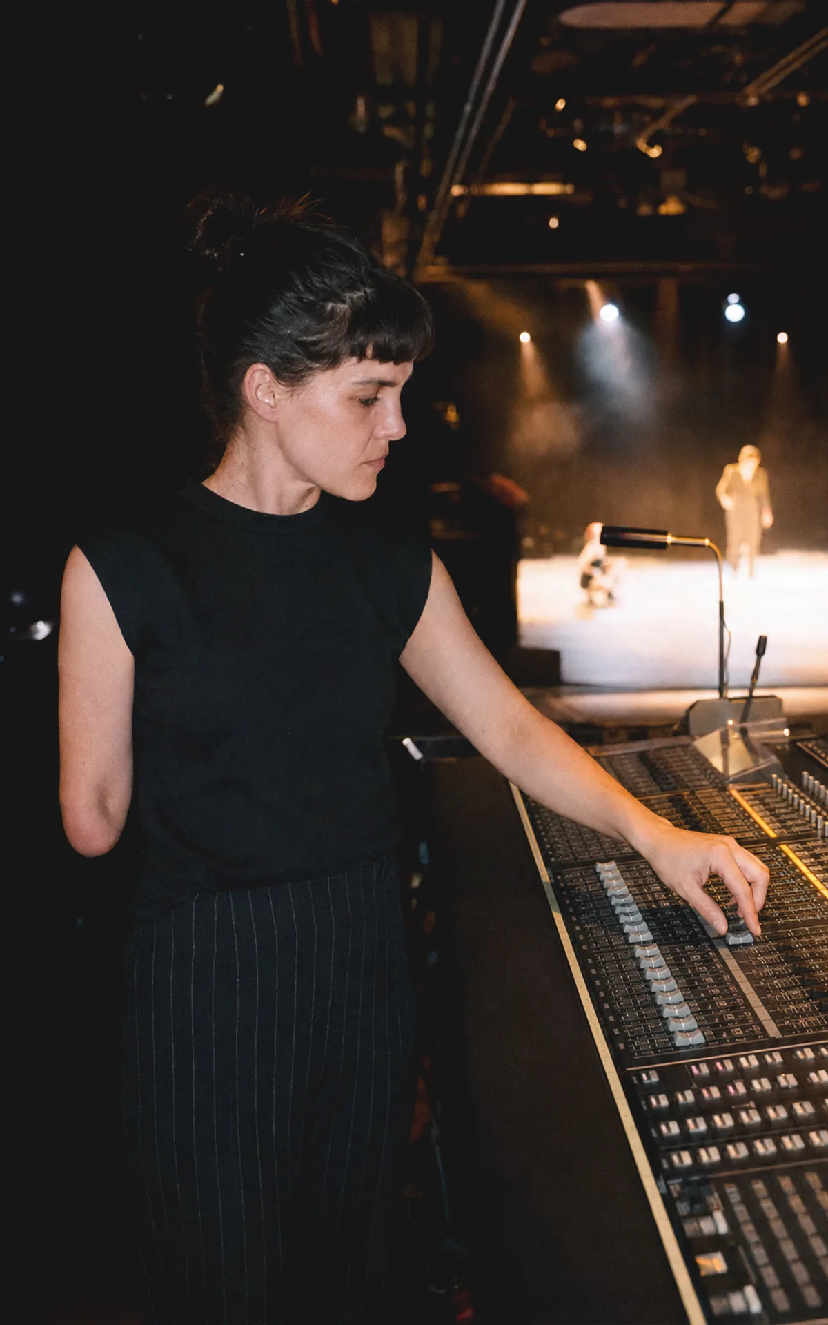 Eine Person mit einer Oberarmdifferenz leitet an einem Lichtpult eine Theaterprobe in Wien.