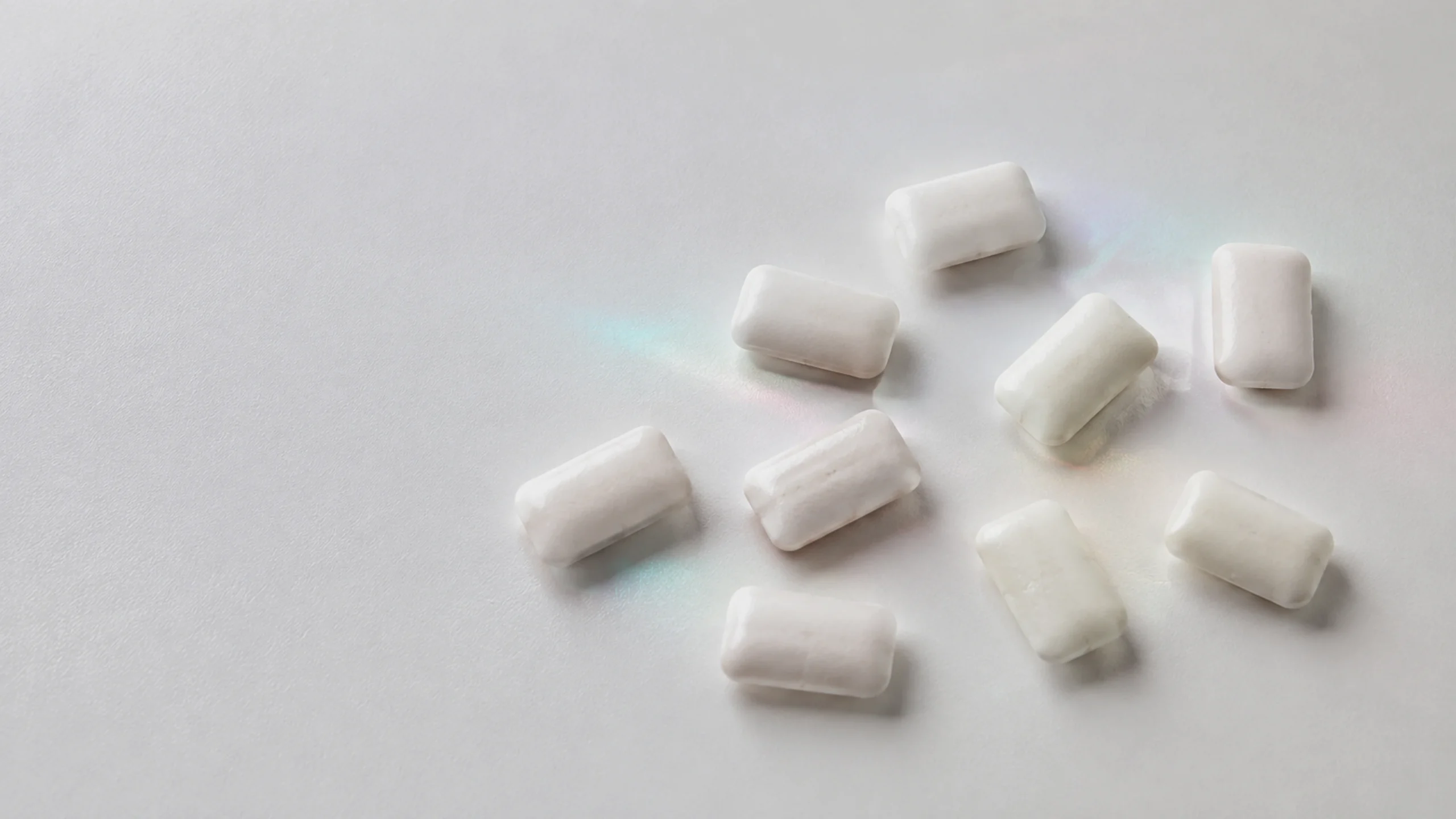 Plusieurs chewing-gums à la xylitol sur un fond clair, illustrant un produit courant contenant ce polyol.