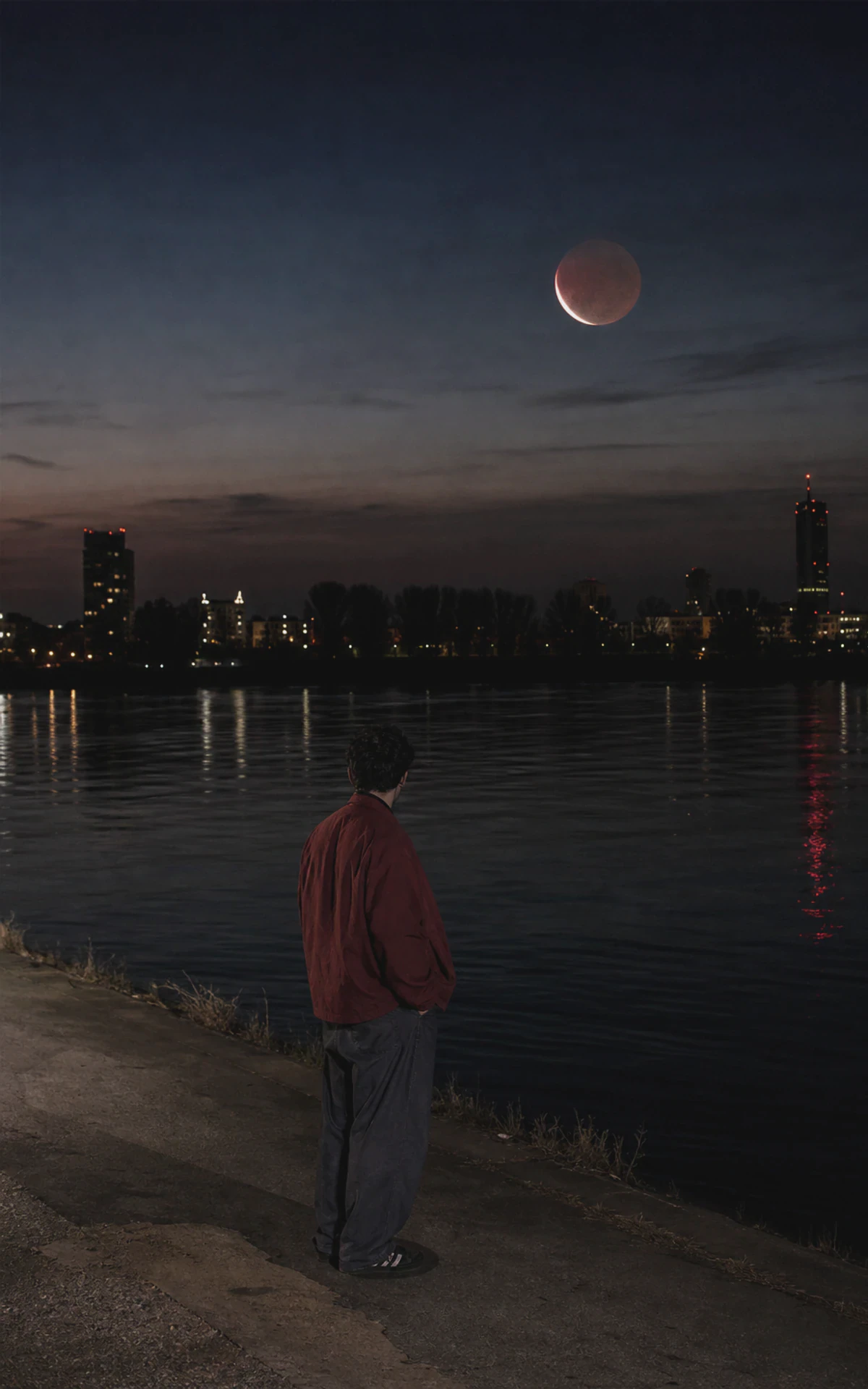 Junger Mensch beobachtet die Mondfinsternis in den Fischen an der Donau in Wien