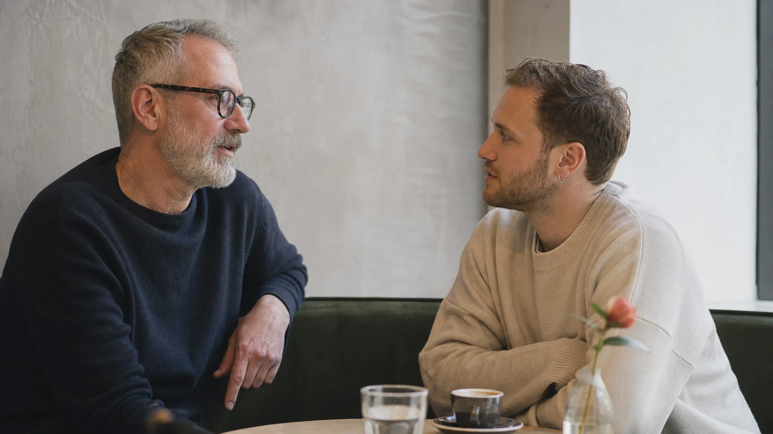 Zwei Männer unterschiedlichen Alters führen in einem Wiener Kaffeehaus ein ruhiges Gespräch.