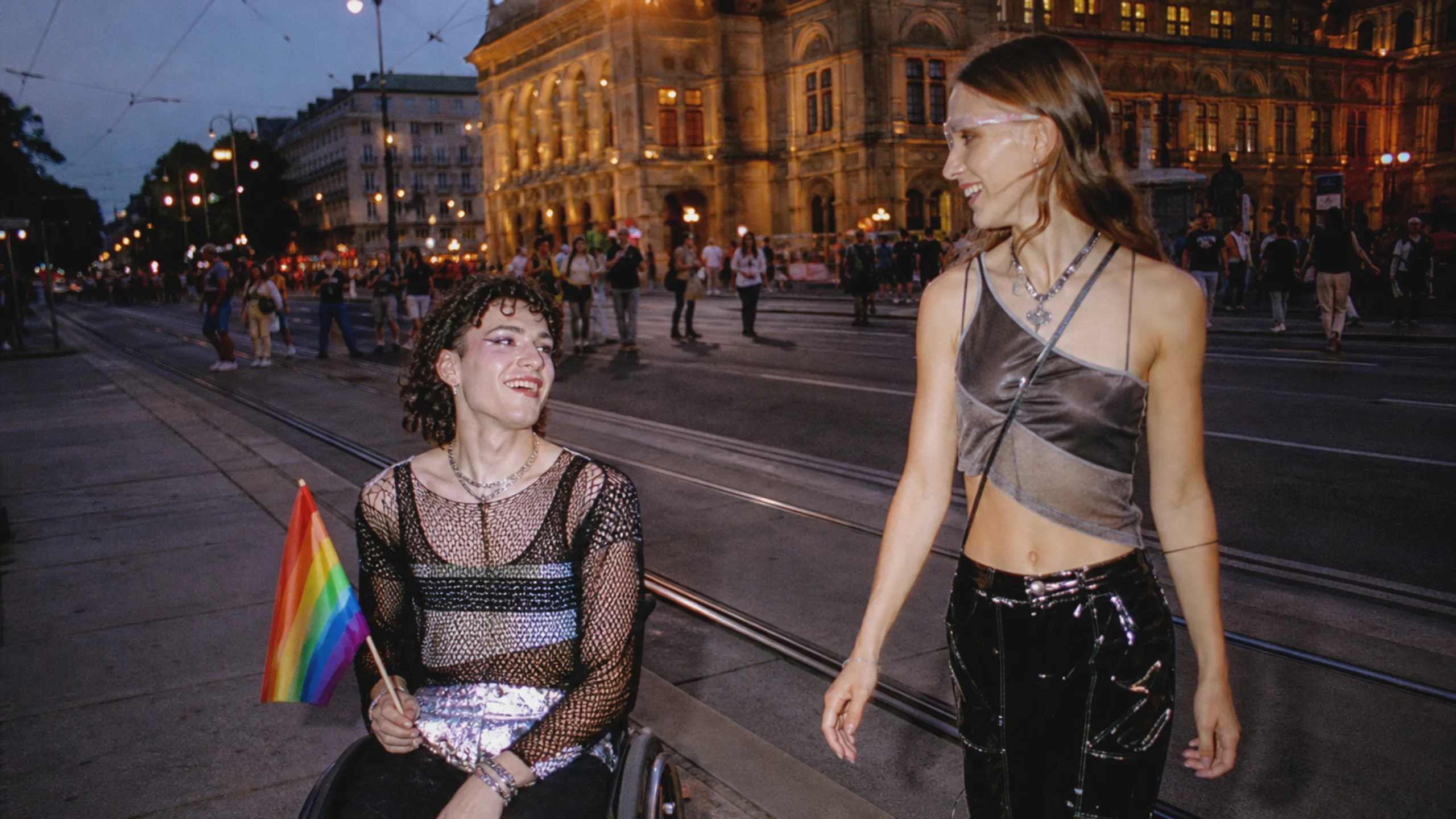 Zwei junge queere Menschen, eine Person im Rollstuhl, nach der Wiener Regenbogenparade.