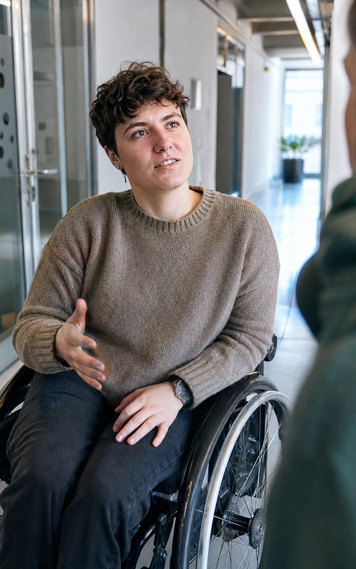 Ein junger behinderter Erwachsener nimmt an einem Gespräch in einem gemeinsam genutzten Arbeitsbereich teil.