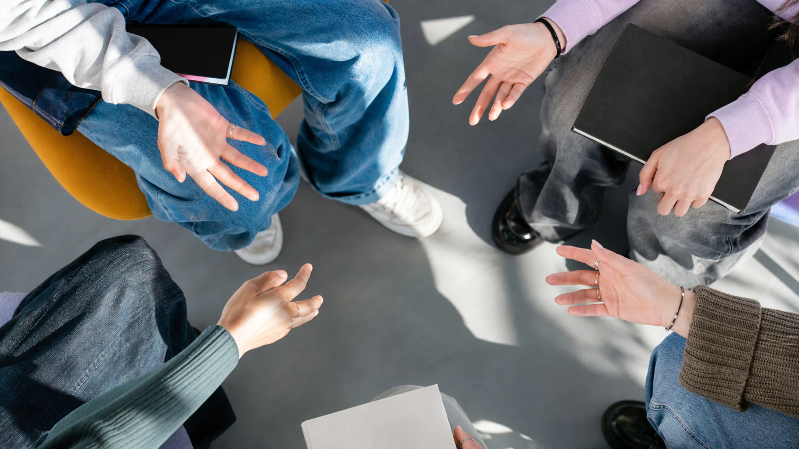 Les mains de jeunes adultes accompagnent une négociation animée dans un cadre éducatif.